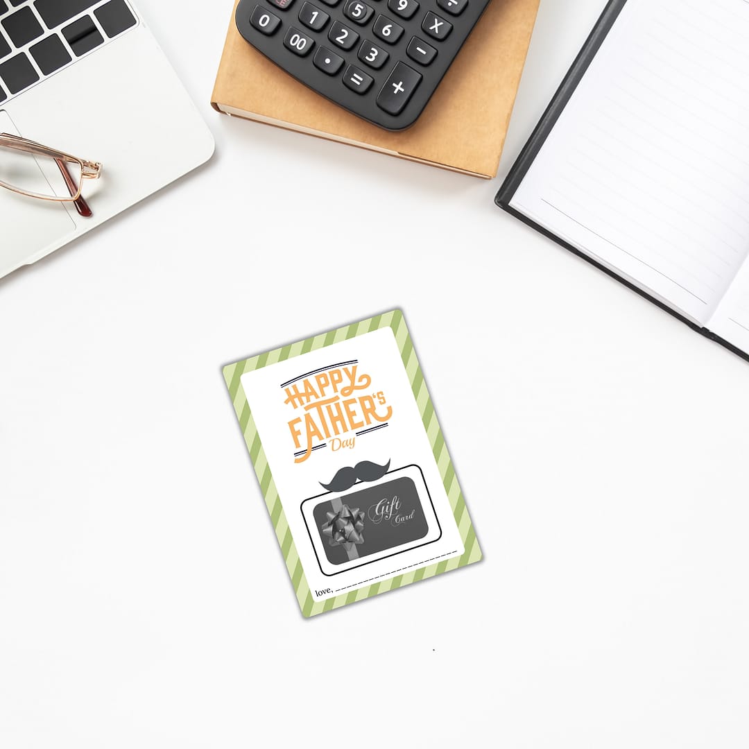 A "Father's Day Gift Card Holder" rests elegantly on a white desk, nestled beside glasses, a calculator, and an open notebook.