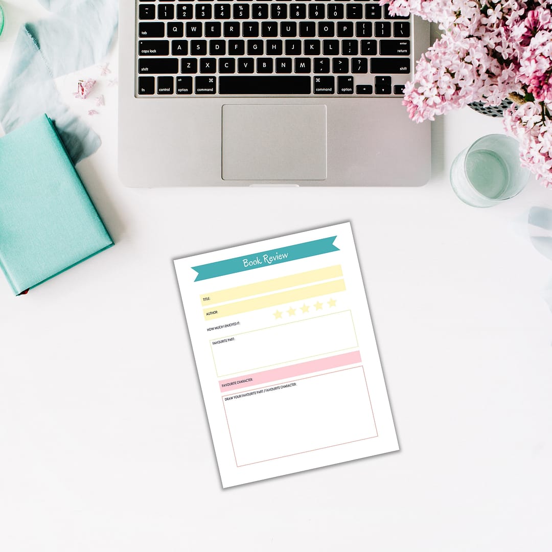 Open your laptop, place the teal notebook and book review form on a white desk adorned with pink flowers in the top corner. This setup is perfect for exploring the Summer Reading Planner for Kids, helping you and your little ones set reading goals for those sunny days ahead.
